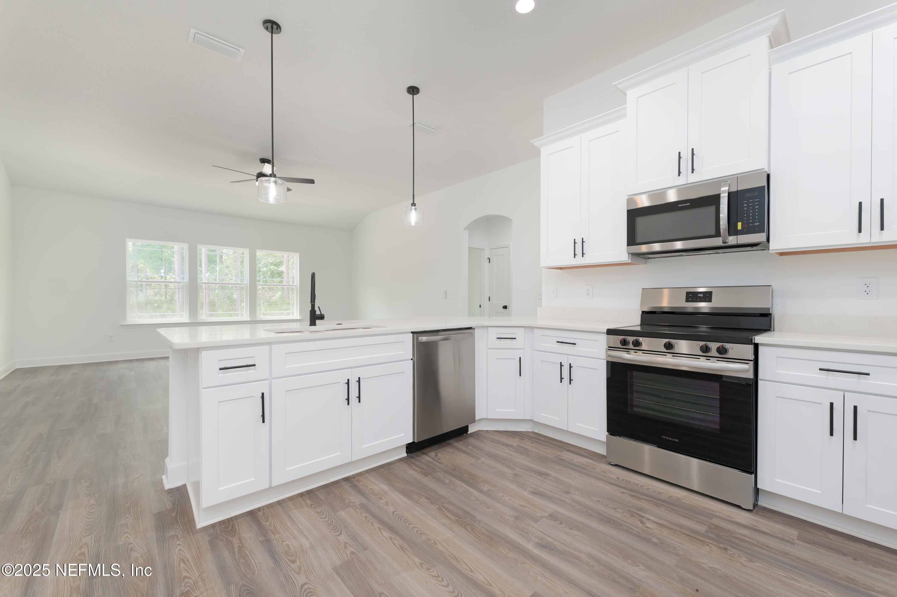 4596 Mayflower Street Middleburg, FL 32068 - Photo 9 of 31 a kitchen with stainless steel appliances white cabinets a sink a stove a microwave and wooden floors