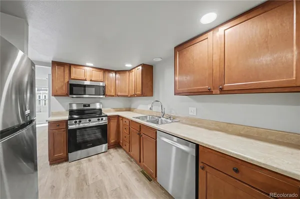 a kitchen with stainless steel appliances granite countertop a stove a sink dishwasher a refrigerator and cabinets with wooden floor
