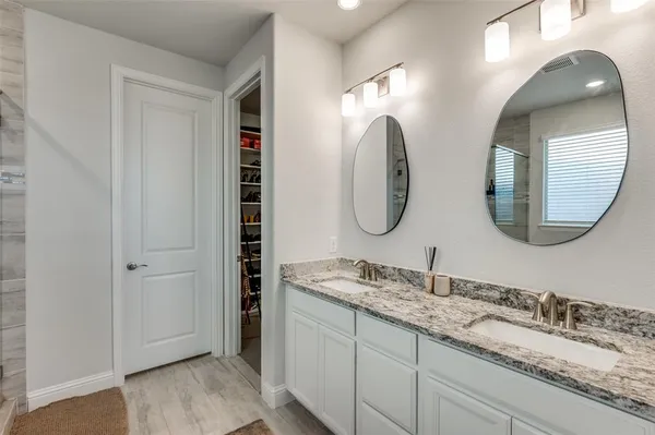 a bathroom with a granite countertop double vanity sinks and a mirror