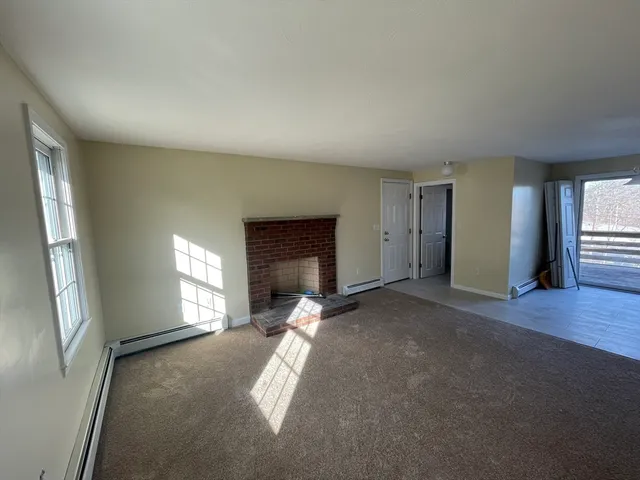 an empty room with windows and fireplace