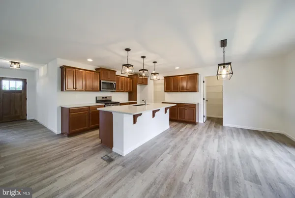 a kitchen with stainless steel appliances a stove top oven a sink dishwasher and a microwave oven on the wooden floor