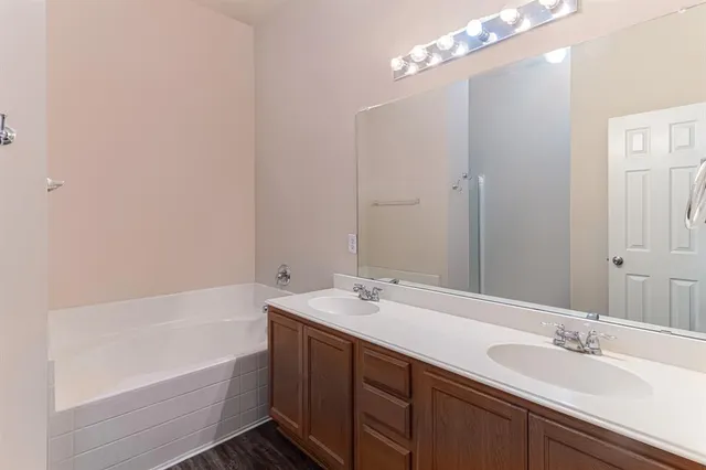 a bathroom with a tub a sink and mirror