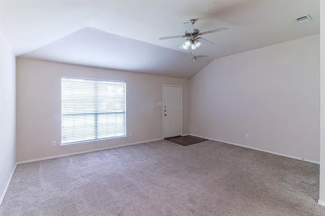 an empty room with chandelier fan and windows