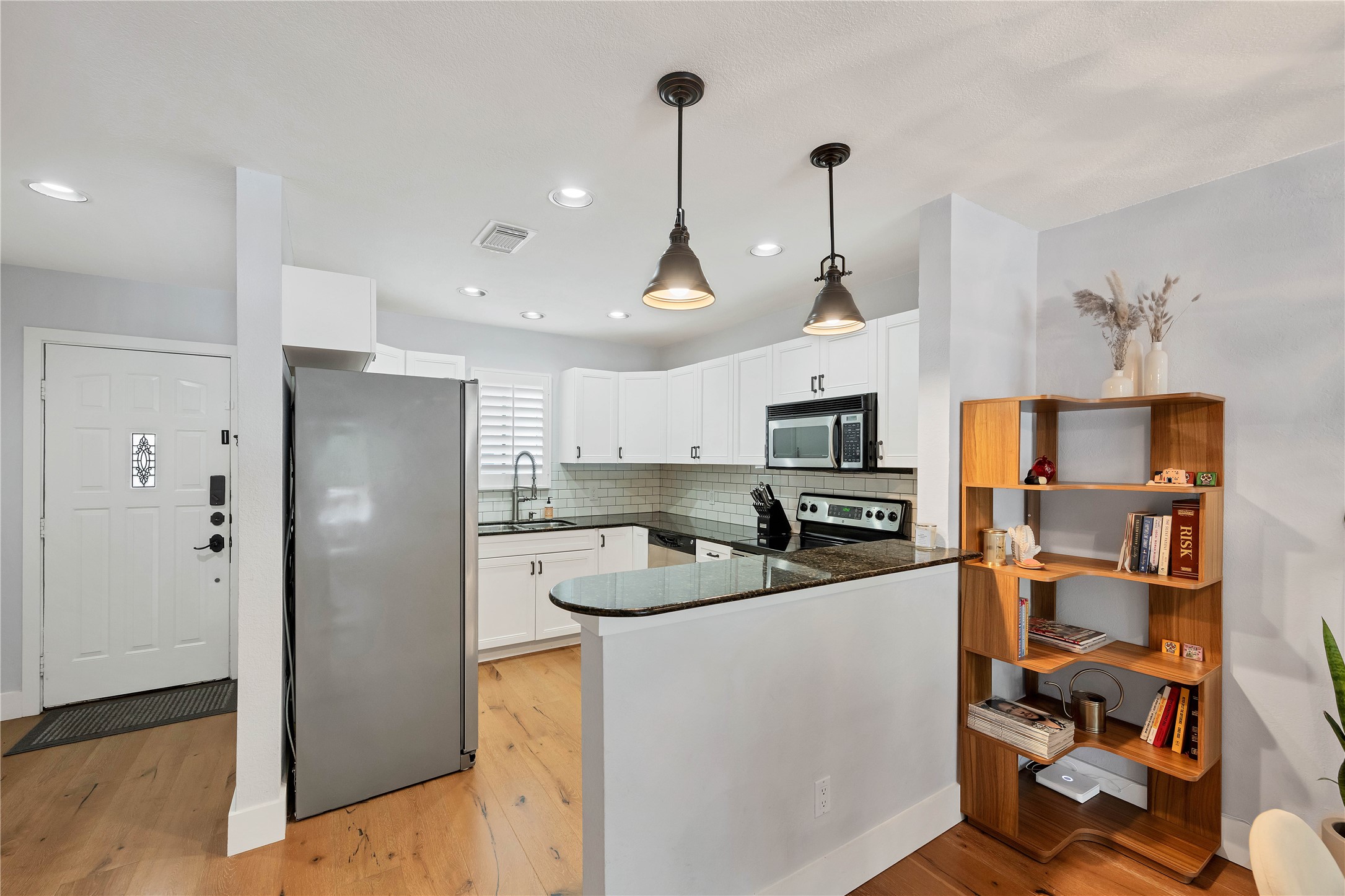 2605 Enfield Road, Unit 221 Austin, TX 78703 - Photo 10 of 30 Updated kitchen features white cabinets, dark granite, stainless steel appliances, breakfast bar, and recessed lighting.