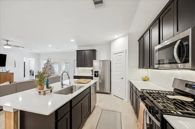 a kitchen with a refrigerator a stove a sink and cabinets