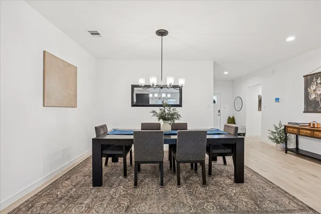 a view of a dining room and livingroom with furniture wooden floor a rug a fireplace and a chandelier