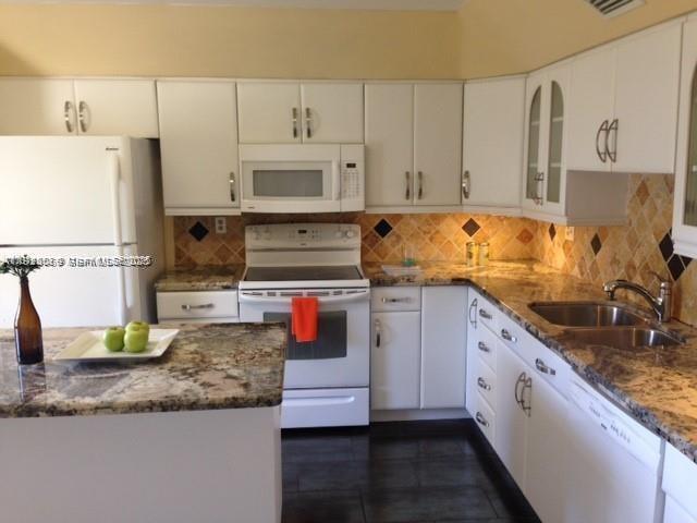 3910 Inverrary Boulevard, Unit 304B Lauderhill, FL 33319 - Photo 1 of 22 a kitchen with kitchen island granite countertop a sink a stove and white cabinets