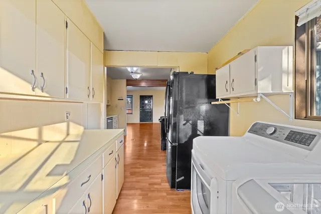 a dining hall with stainless steel appliances kitchen island granite countertop a refrigerator a sink dishwasher and white cabinets next to a window
