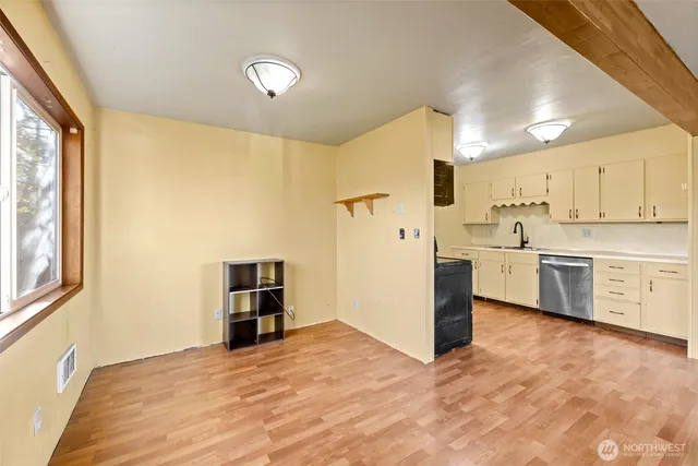 a view of a kitchen with a sink and dishwasher a refrigerator with wooden floor