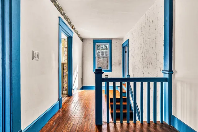 a view of a hallway with wooden floor and stairs