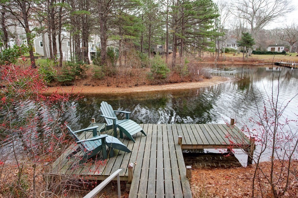 55 Pond Circle Mashpee, MA 02649 - Photo 34 of 40 a view of a wooden deck and lake with trees in the background