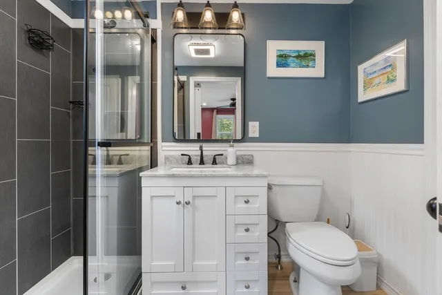 a bathroom with a toilet sink vanity and mirror