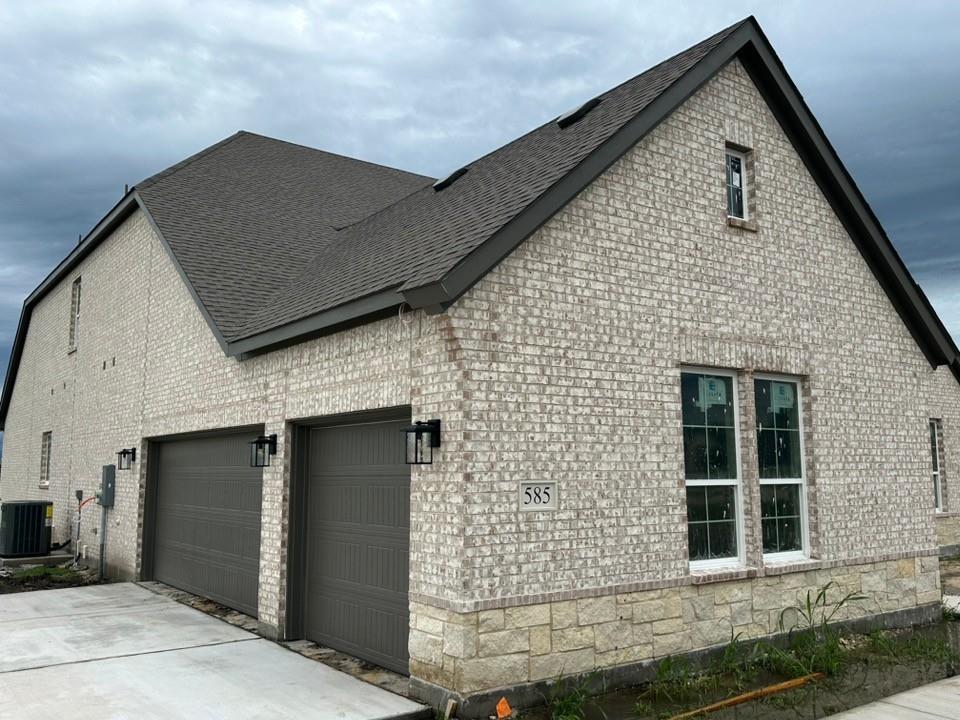 585 Brown Road Leonard, TX 75452 - Photo 3 of 29 Two-car garage with individual doors, complemented by a light brick and stone facade