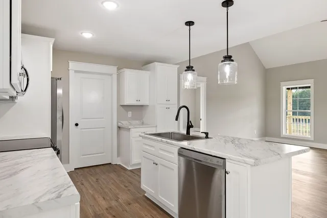 a kitchen that has a sink stainless steel appliances a counter tops and a wooden floors