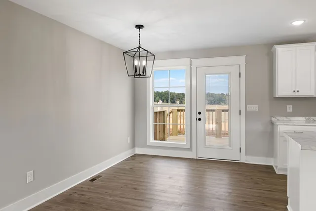 a view of empty room with wooden floor and window