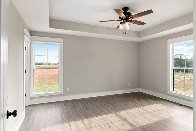 a view of empty room with wooden floor and fan