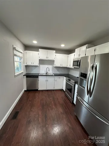 a kitchen with stainless steel appliances granite countertop a refrigerator sink and white cabinets