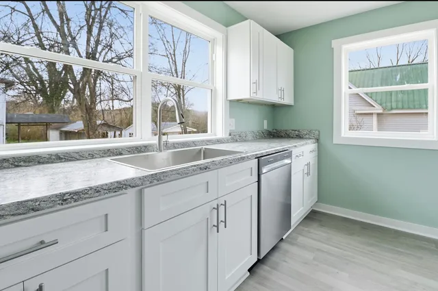 a kitchen with granite countertop white cabinets and a sink