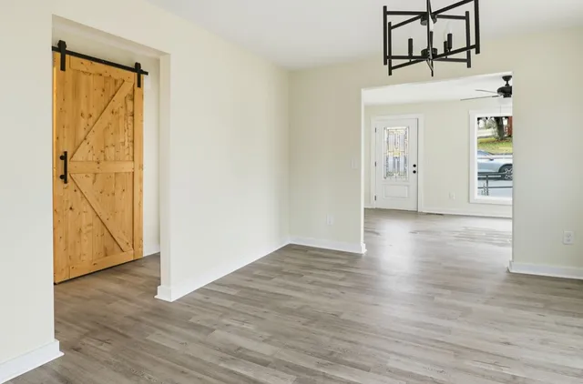 an empty room with wooden floor closet and windows