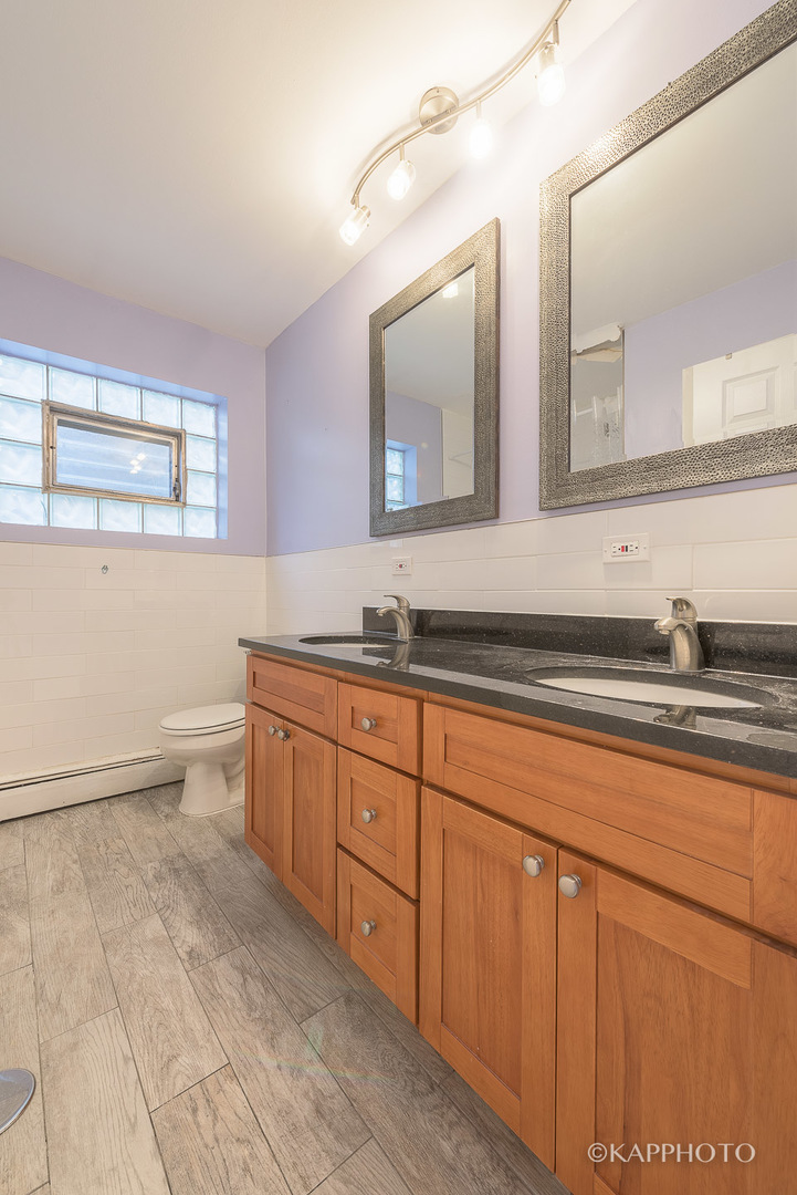5942 West Addison Street, Unit 1 Chicago, IL 60634 - Photo 21 of 24 a spacious bathroom with a granite countertop sink a toilet and mirror