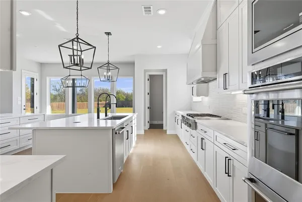 a large kitchen with stainless steel appliances granite countertop a stove and a sink