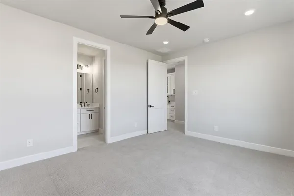 an empty room with a bathroom and a ceiling fan