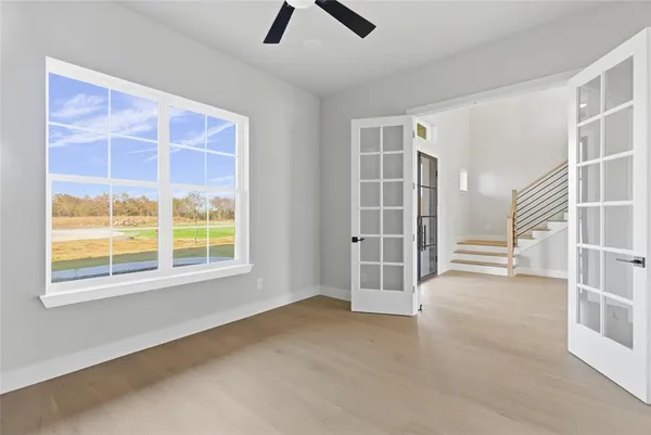 an empty room with chandelier fan and windows