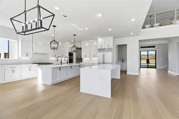 a large kitchen with kitchen island a large counter space a sink stainless steel appliances and cabinets