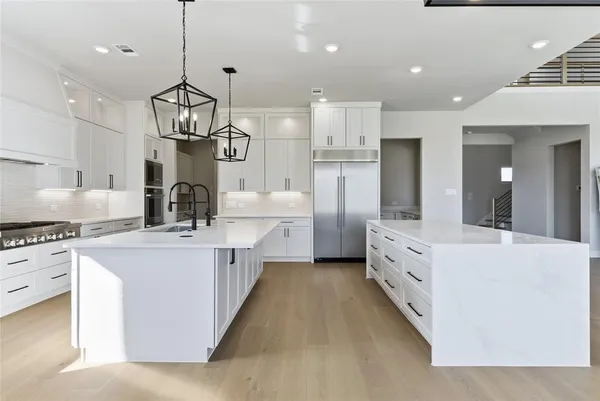 a large kitchen with stainless steel appliances granite countertop a sink a stove and a refrigerator