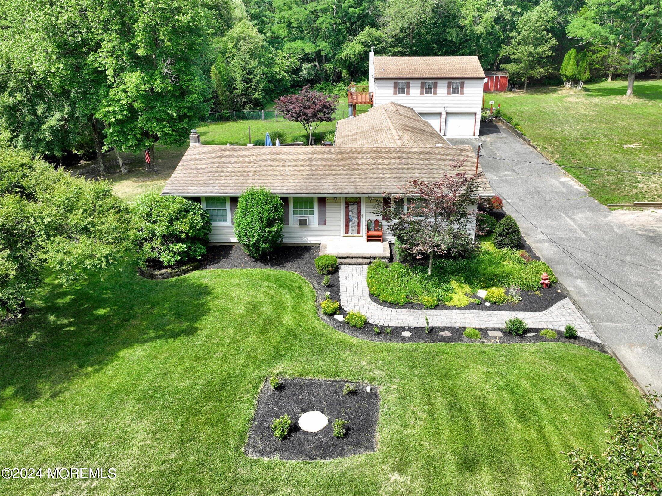 155 Tyrpak Road Howell, NJ 07731 - Photo 2 of 35 a view of a white house with a yard and table and chairs under an umbrella