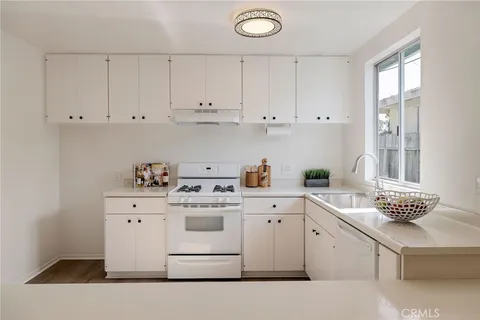 a kitchen with cabinets appliances a sink and a stove top oven