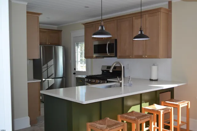 a kitchen with stainless steel appliances a sink a stove a refrigerator a counter top space and cabinets