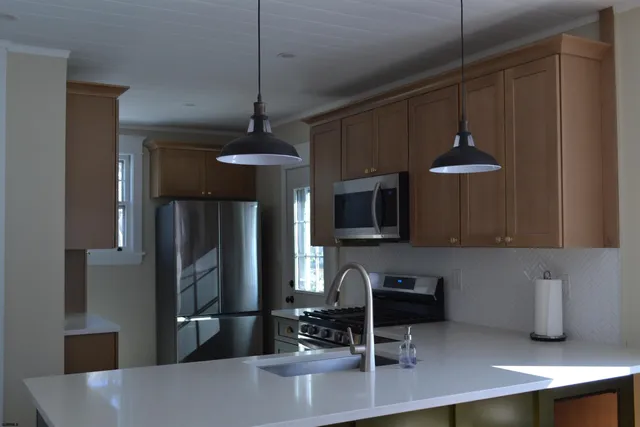 a kitchen with stainless steel appliances a sink a stove a microwave a refrigerator a stove and cabinets