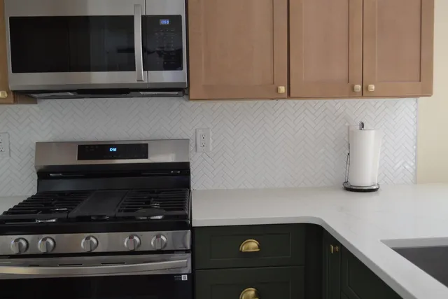 a kitchen with stainless steel appliances granite countertop white cabinets and black stove top oven with granite countertops