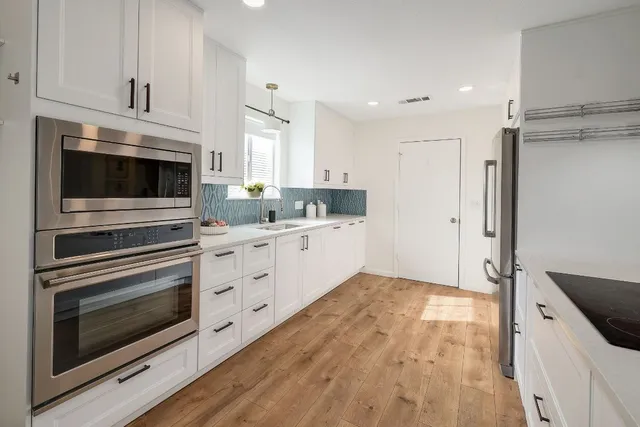 a kitchen with stainless steel appliances white cabinets and a stove top oven