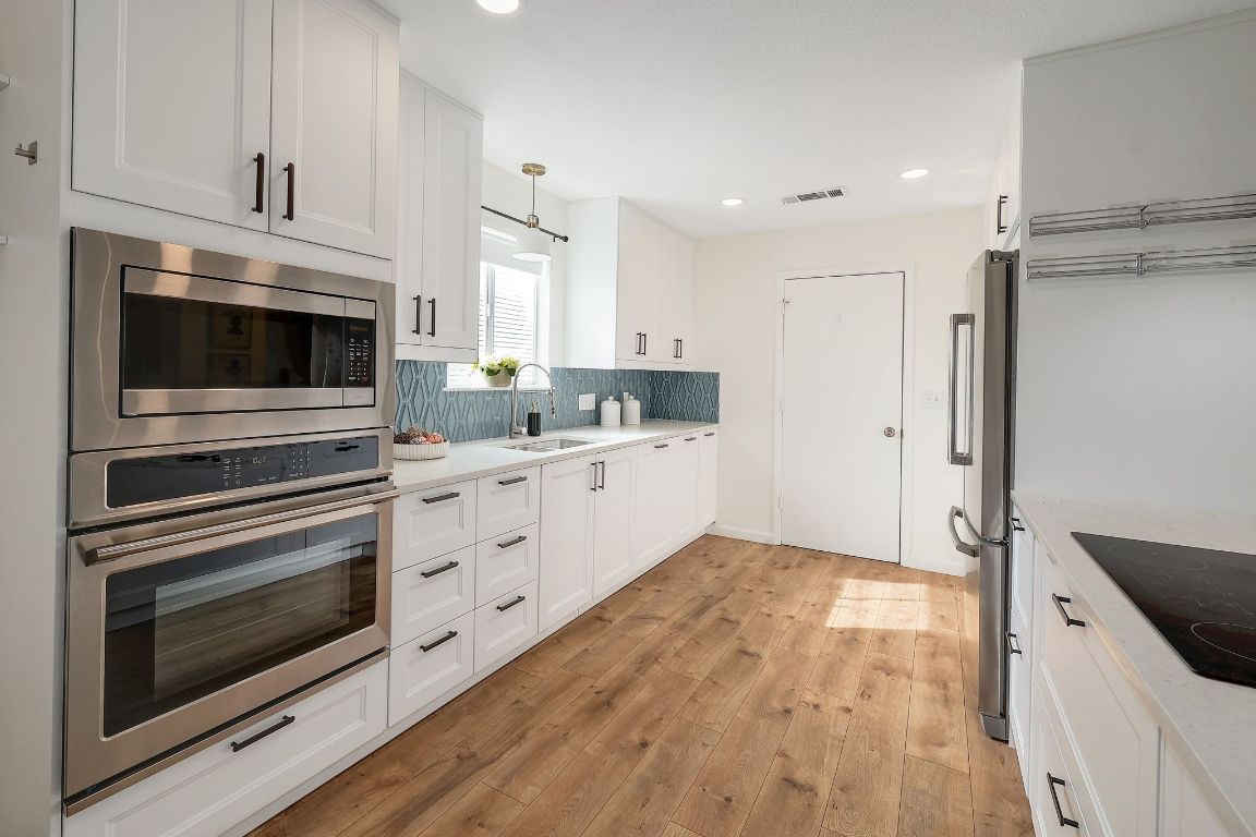 12511 Tree Line Drive Austin, TX 78729 - Photo 12 of 19 a kitchen with stainless steel appliances white cabinets and a stove top oven