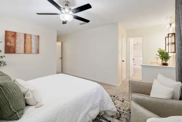 a bedroom with a couch ceiling fan and a wooden floor