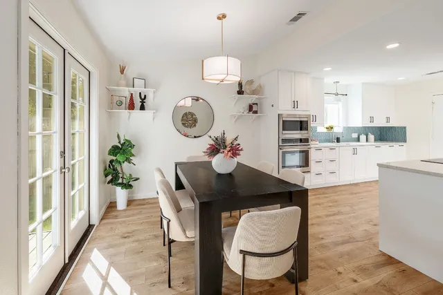 a kitchen with granite countertop a table chairs stove and a dining table with wooden floor