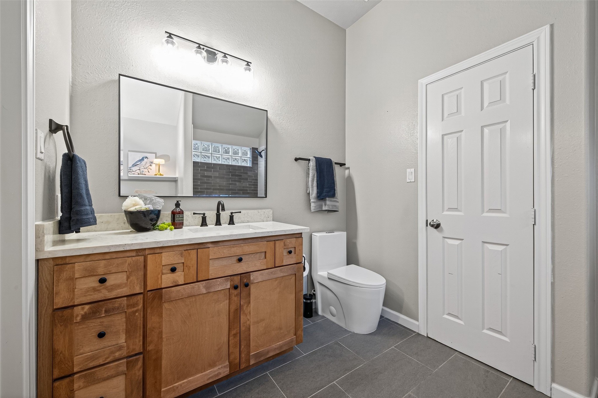 2910 Crescent Bend Road Spring, TX 77388 - Photo 14 of 29 This bathroom features a modern design with a wooden vanity, a large mirror, and sleek fixtures. It has a neutral color palette, ample storage, and a contemporary toilet, creating a clean and inviting space.