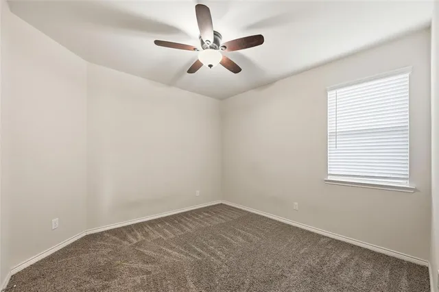 an empty room with ceiling fan and windows