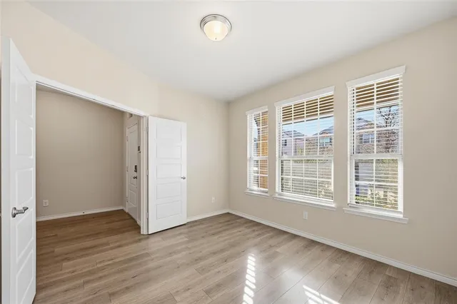 an empty room with wooden floor and windows