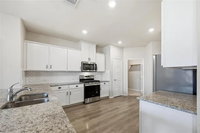 a kitchen with stainless steel appliances granite countertop a sink stove refrigerator and cabinets