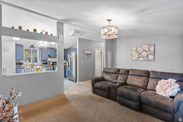 271 Mindella Way Layton, UT 84041 - Photo 5 of 27 Spacious living area featuring neutral carpeting, a decorative ceiling light fixture, and a pass-through window to the kitchen