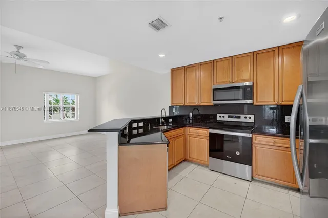 a kitchen with stainless steel appliances granite countertop a stove a sink and a refrigerator