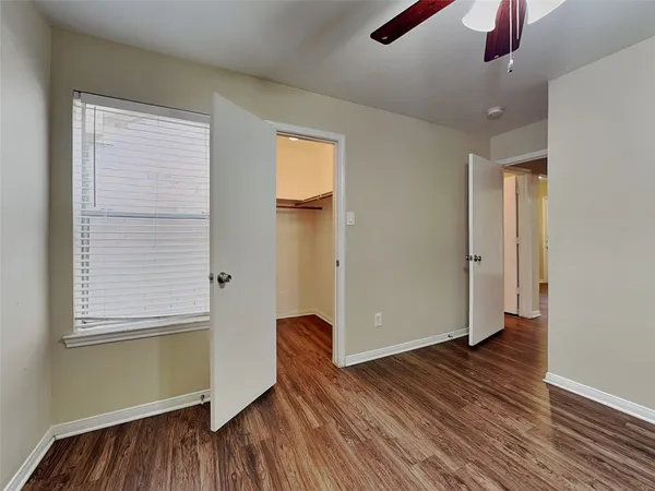 an empty room with wooden floor cabinet and windows