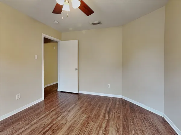 an empty room with wooden floor chandelier fan and closet