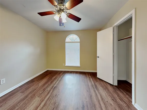 an empty room with wooden floor chandelier fan and windows