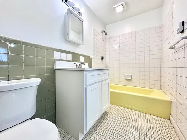 a bathroom with a granite countertop bathtub sink mirror vanity and toilet