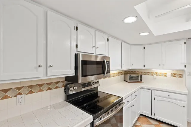 a kitchen with white cabinets and appliances