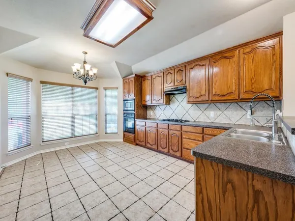 a view of a kitchen with kitchen island granite countertop a sink appliances cabinets and a counter top space